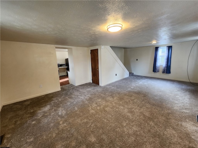 basement with a textured ceiling and dark colored carpet