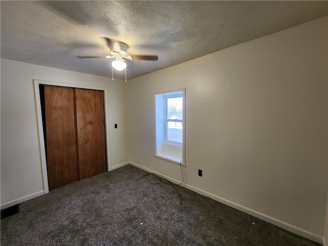 unfurnished bedroom featuring ceiling fan, a textured ceiling, and dark colored carpet