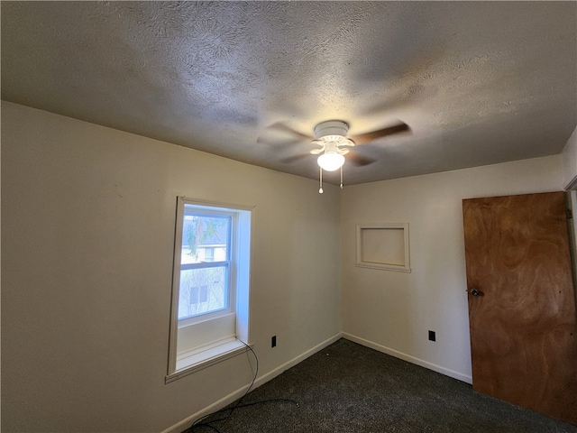 spare room with ceiling fan, dark carpet, and a textured ceiling