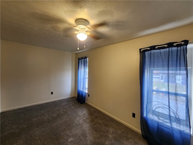 unfurnished room featuring dark colored carpet, a textured ceiling, and ceiling fan