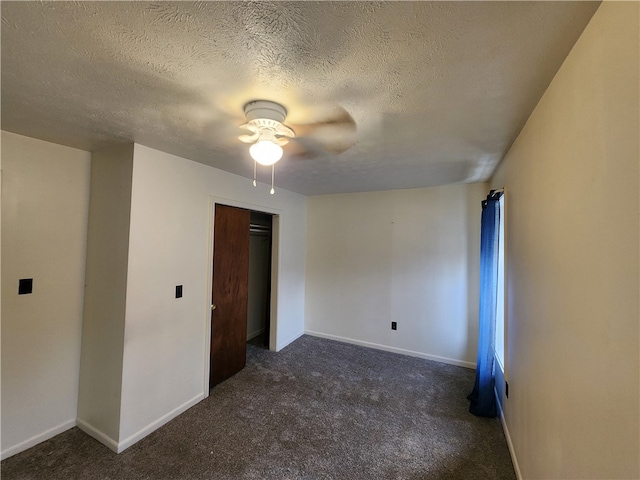 unfurnished bedroom featuring dark colored carpet, a textured ceiling, a closet, and ceiling fan