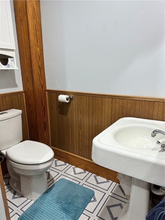 bathroom featuring wooden walls and toilet