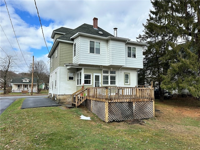 rear view of property featuring a yard and a wooden deck