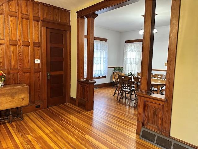 hall with decorative columns and light hardwood / wood-style flooring