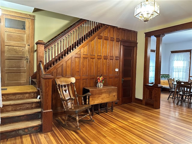 interior space featuring decorative columns, light hardwood / wood-style floors, and a notable chandelier