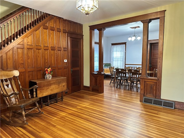 interior space with ornate columns, a chandelier, and wood-type flooring