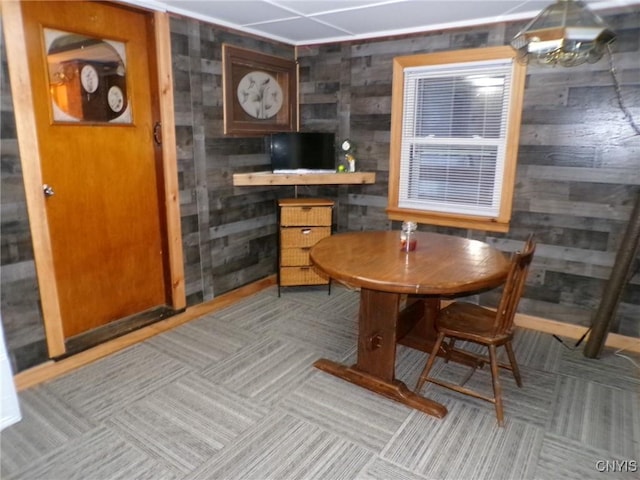 dining space with light colored carpet and wooden walls