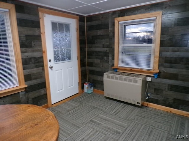 doorway with carpet and wood walls