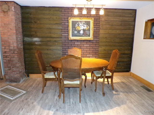 dining area with wood walls and wood-type flooring