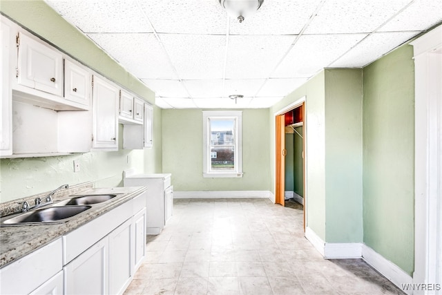 kitchen with white cabinets, a paneled ceiling, and sink