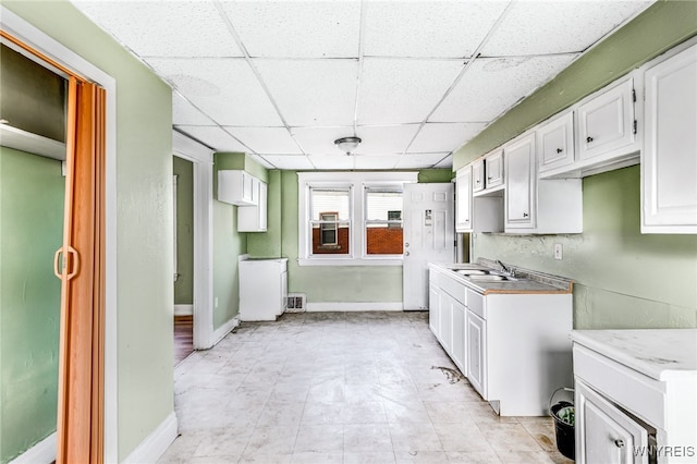 kitchen with white cabinets, a paneled ceiling, and sink