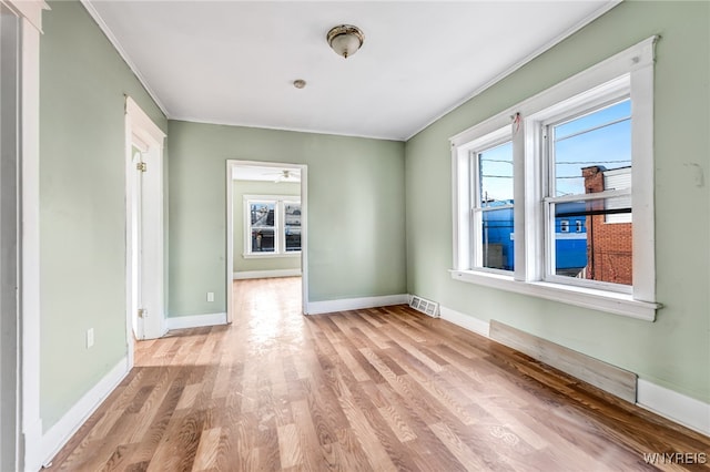 empty room with ceiling fan, ornamental molding, and light hardwood / wood-style flooring