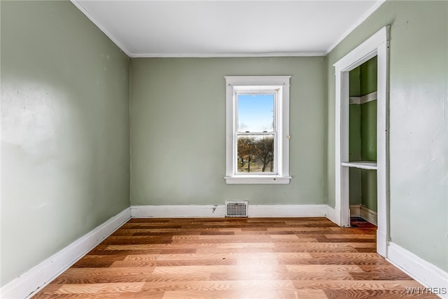 empty room featuring hardwood / wood-style flooring and ornamental molding