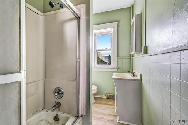 full bathroom with hardwood / wood-style floors, toilet, shower / tub combination, vanity, and tile walls