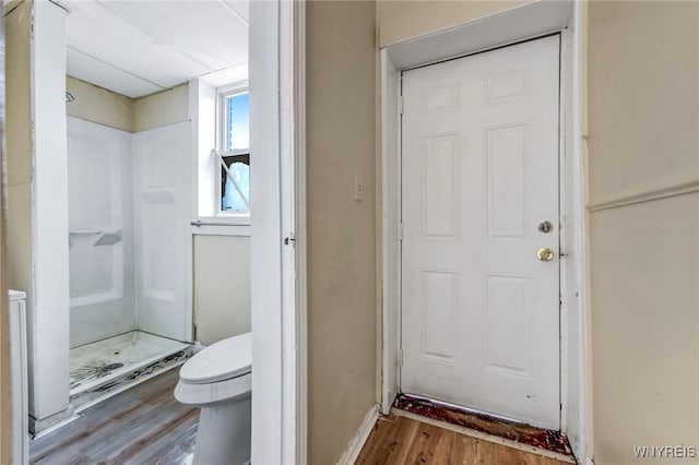 bathroom with toilet, wood-type flooring, and walk in shower