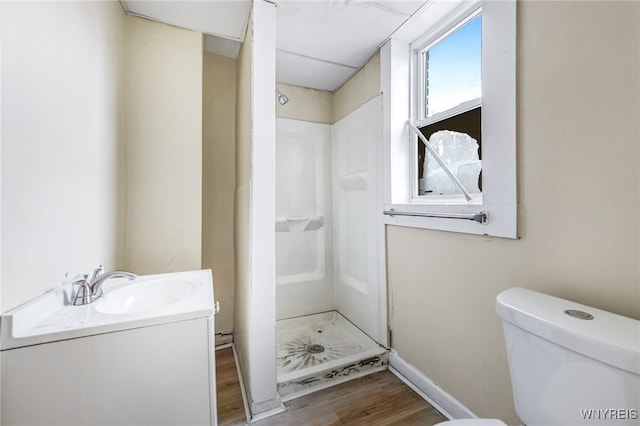 bathroom featuring hardwood / wood-style flooring, vanity, toilet, and a shower