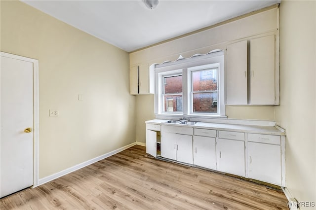 kitchen with white cabinetry, light hardwood / wood-style flooring, and sink