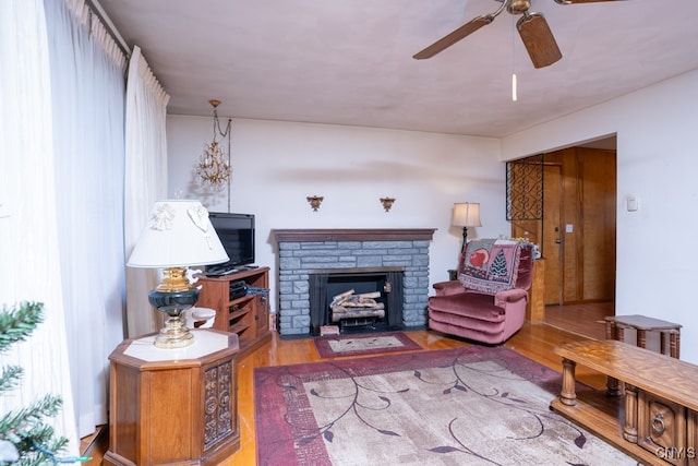 living room with light hardwood / wood-style flooring, ceiling fan, and a stone fireplace