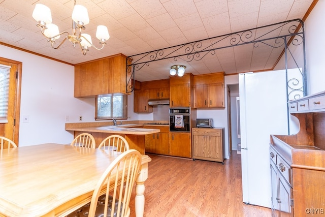 kitchen with stainless steel gas cooktop, light hardwood / wood-style flooring, kitchen peninsula, crown molding, and black oven