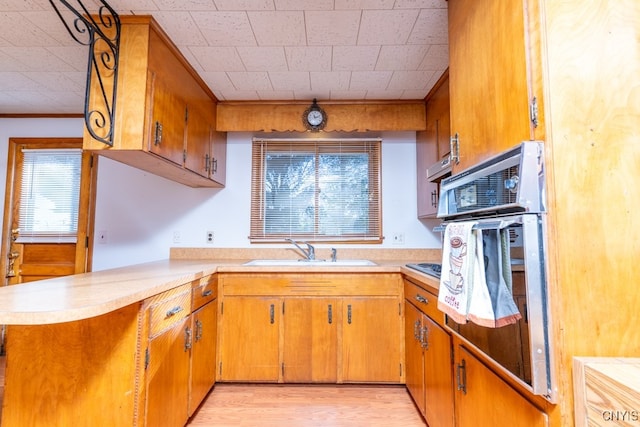 kitchen featuring kitchen peninsula, light hardwood / wood-style floors, oven, and sink