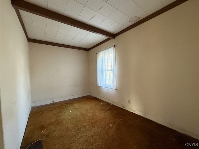 empty room featuring beamed ceiling, carpet floors, and crown molding