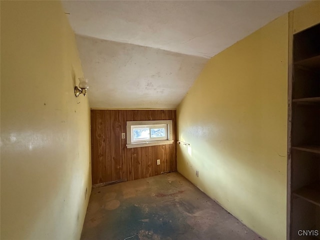 interior space featuring concrete floors, lofted ceiling, and wood walls