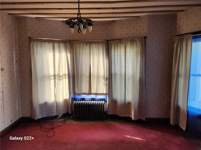 carpeted empty room featuring an inviting chandelier, plenty of natural light, and radiator