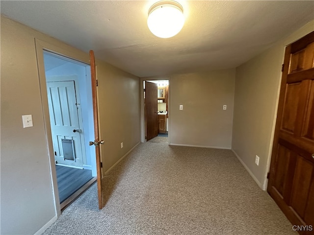 hall featuring light carpet and a textured ceiling