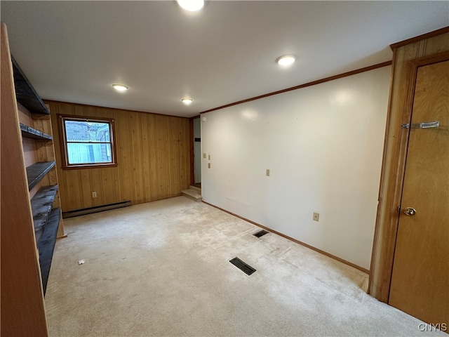 interior space featuring light colored carpet, ornamental molding, wooden walls, and a baseboard radiator