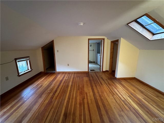 bonus room with hardwood / wood-style floors and vaulted ceiling with skylight