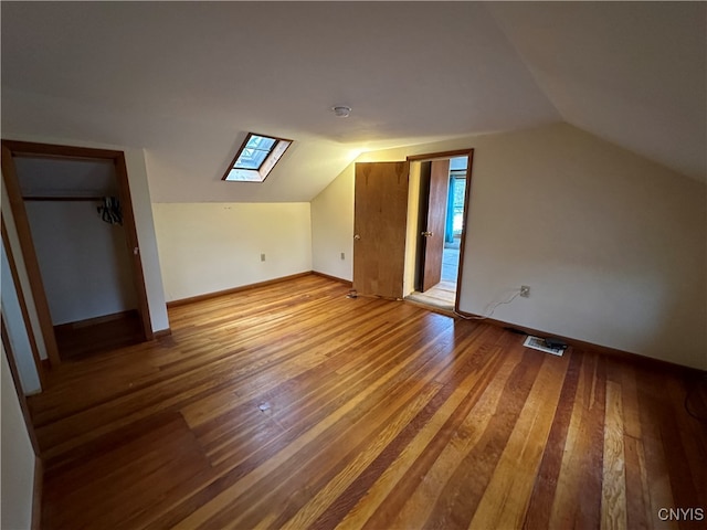 additional living space featuring hardwood / wood-style floors and lofted ceiling with skylight