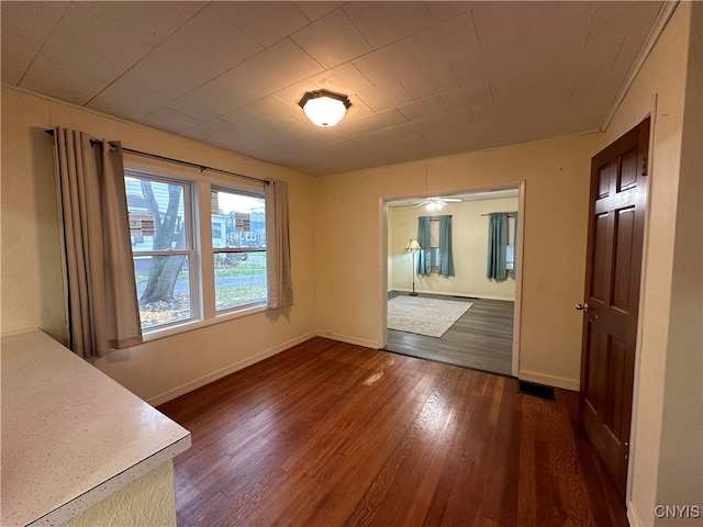 unfurnished dining area with ceiling fan and dark wood-type flooring