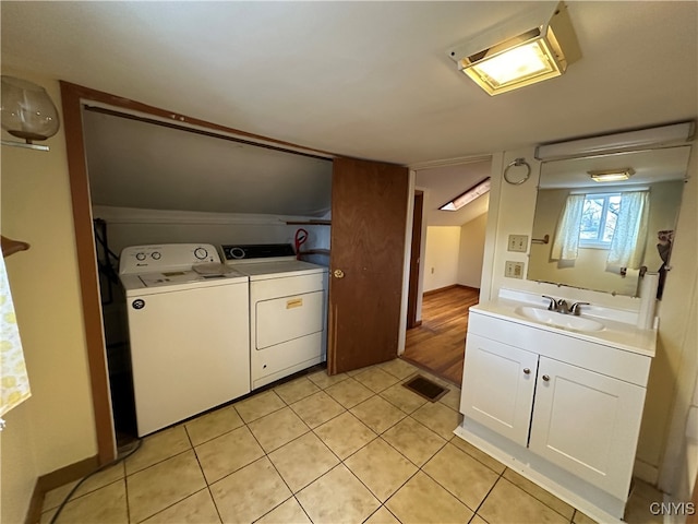 clothes washing area with washing machine and dryer, light tile patterned floors, and sink