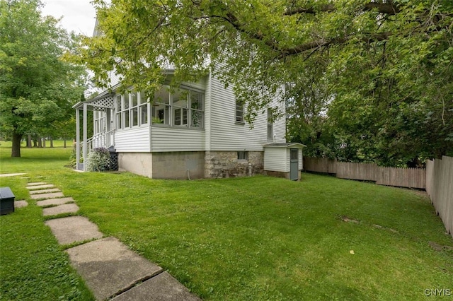 view of side of home with a lawn, a sunroom, and a shed