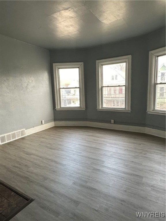 unfurnished room featuring dark wood-style floors, visible vents, and baseboards