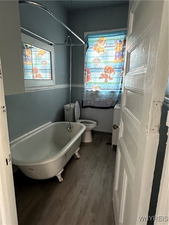 bathroom featuring toilet, a freestanding bath, and wood finished floors