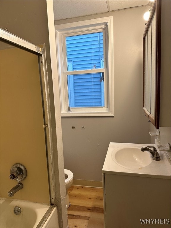 bathroom featuring toilet, vanity, shower / tub combination, wood finished floors, and baseboards