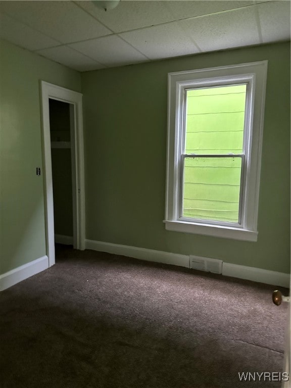 empty room featuring visible vents, carpet flooring, a drop ceiling, and baseboards