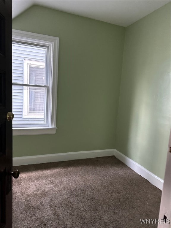 carpeted spare room with a wealth of natural light, lofted ceiling, and baseboards