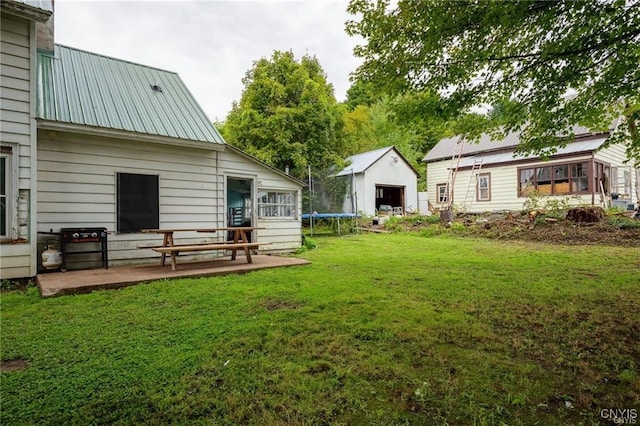 view of yard with an outbuilding, a trampoline, and a patio area