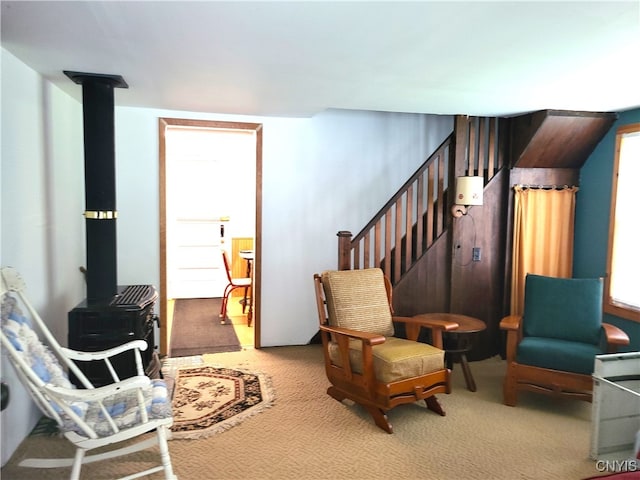 sitting room featuring carpet flooring, a wood stove, and plenty of natural light