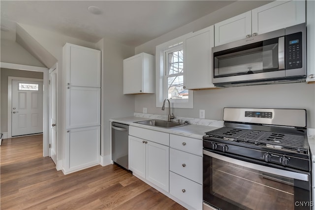 kitchen with sink, white cabinets, light hardwood / wood-style floors, and appliances with stainless steel finishes