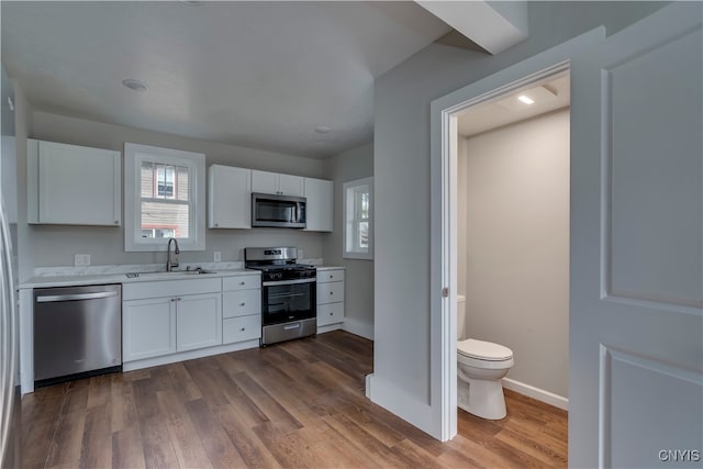 kitchen featuring appliances with stainless steel finishes, hardwood / wood-style flooring, white cabinetry, and sink