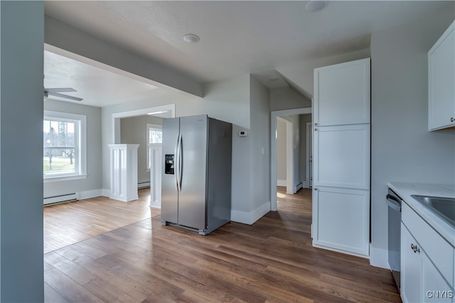 kitchen featuring hardwood / wood-style floors, ceiling fan, baseboard heating, appliances with stainless steel finishes, and white cabinetry