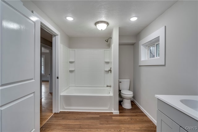 full bathroom with washtub / shower combination, hardwood / wood-style floors, a textured ceiling, toilet, and vanity