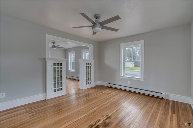 spare room with light wood-type flooring, ceiling fan, and a baseboard heating unit