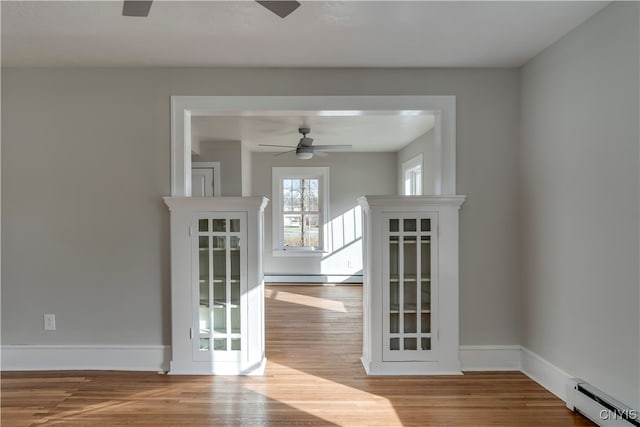 spare room featuring ceiling fan, light wood-type flooring, and a baseboard heating unit