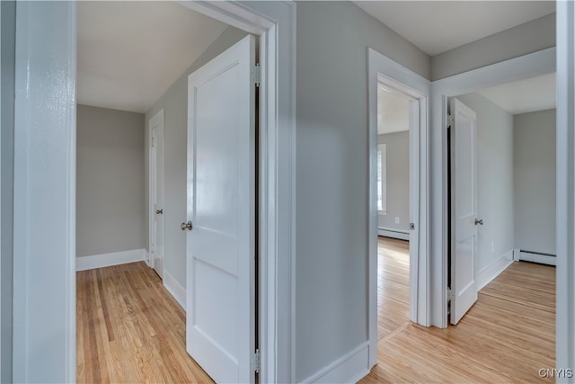 hallway with light hardwood / wood-style floors and a baseboard radiator