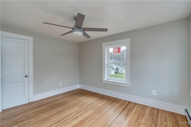 empty room featuring ceiling fan, light hardwood / wood-style floors, and a baseboard heating unit