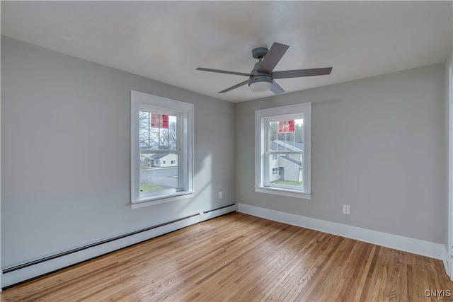 empty room featuring plenty of natural light, baseboard heating, and light hardwood / wood-style flooring